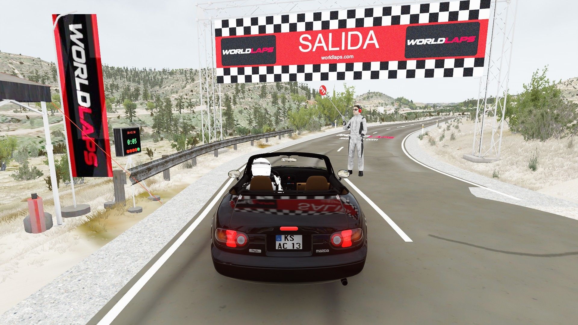 Assetto Corsa screenshot at the start of the Buñol stage: the SALIDA gantry with the start clock, the guardrail and the pine trees.