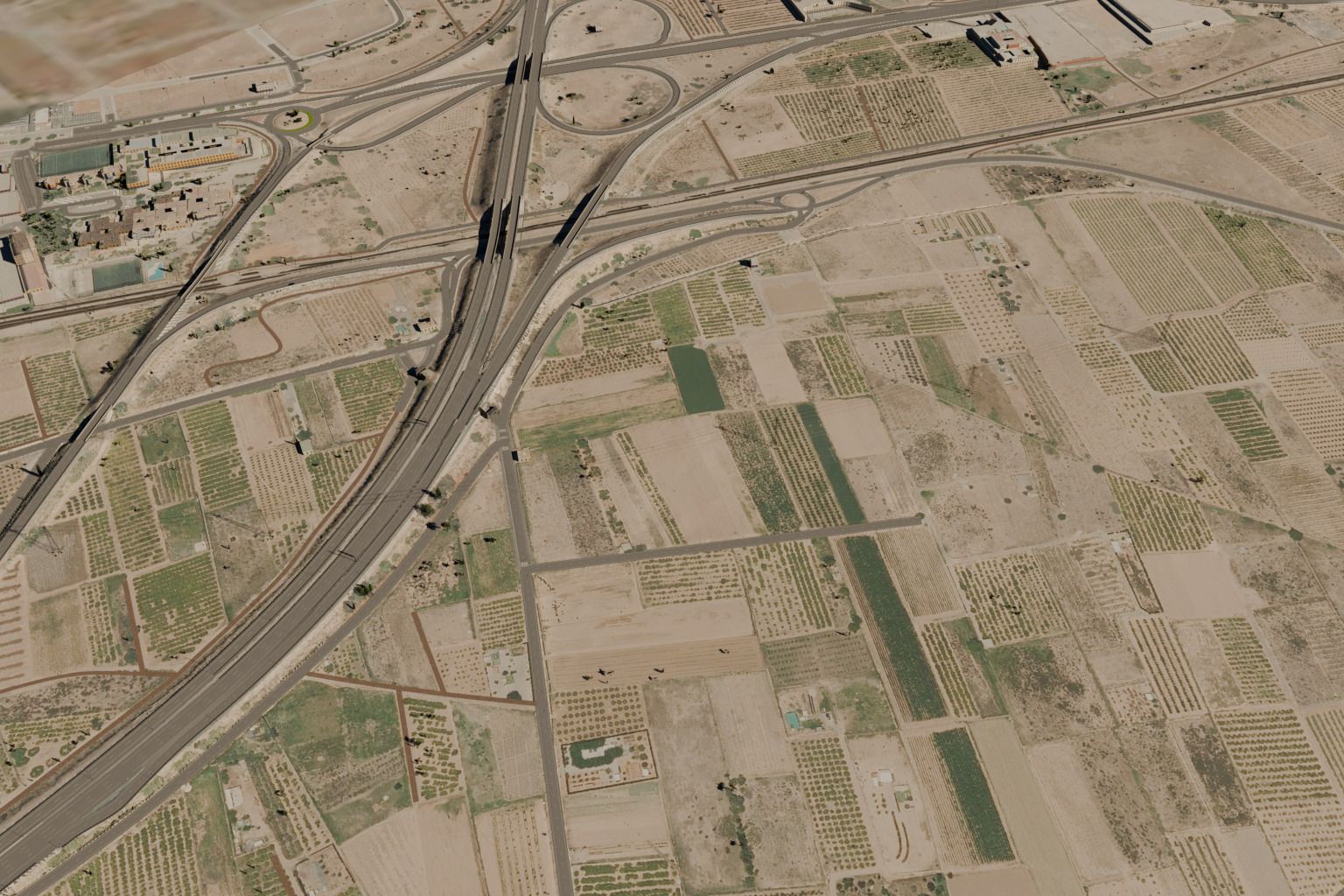 Vista aérea de la salida de autopista: el enlace con sus puentes, la vía del tren y los campos de naranjos alrededor.